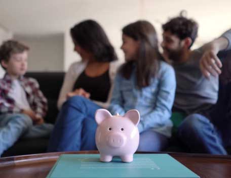 A family sitting on a couch with a piggy bank on a table