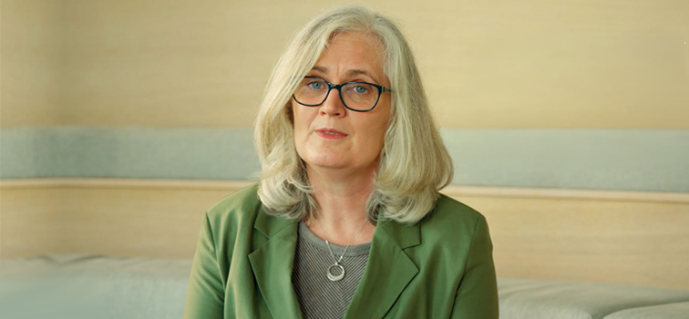 A woman with long blonde hair wearing a green jacket