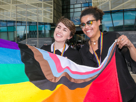 Two women holding the pride flag