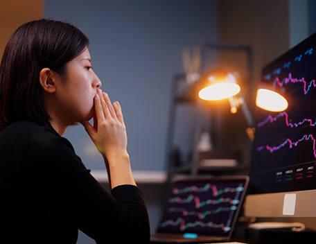 A woman looking at two computer screens